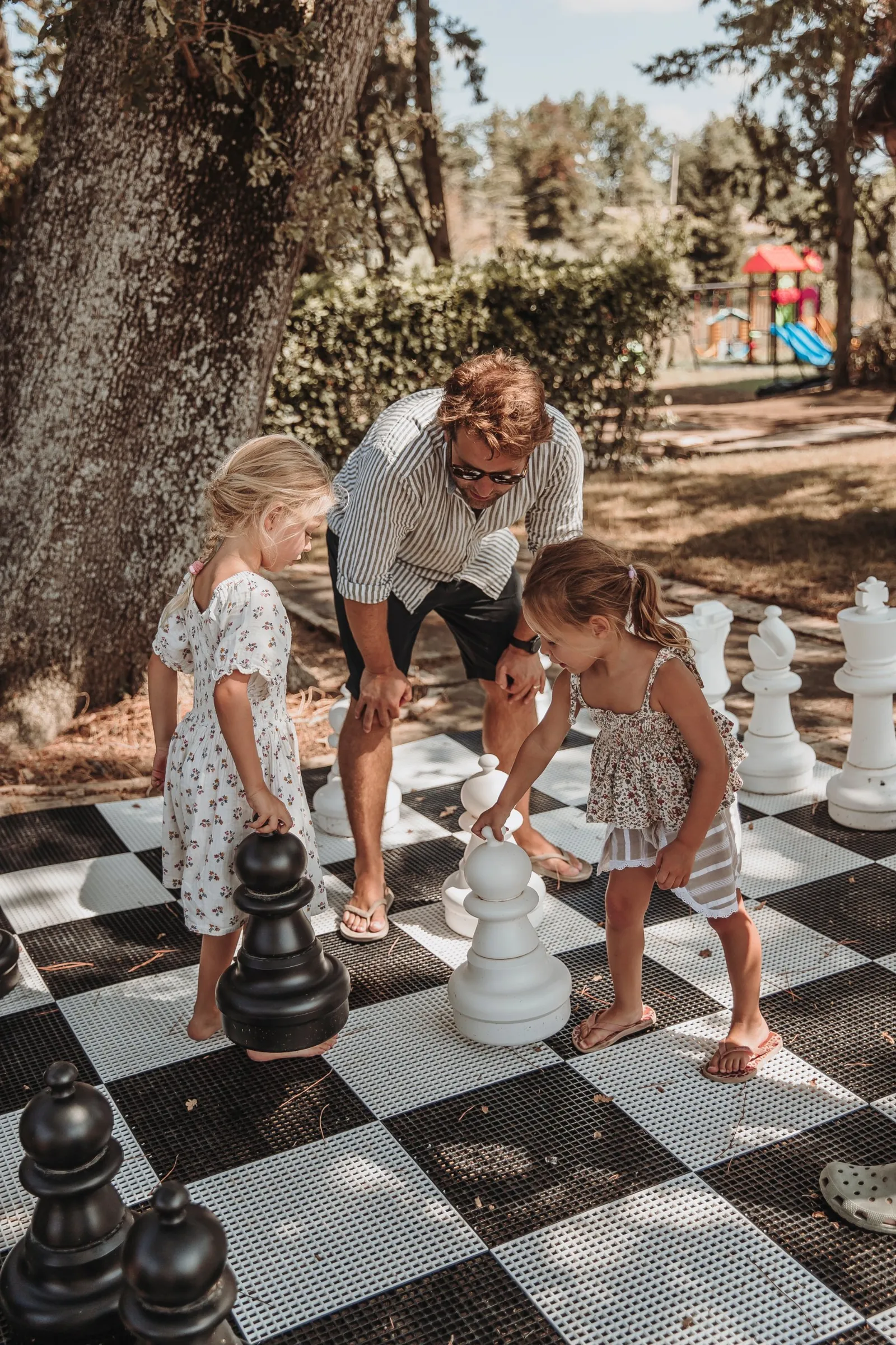 Children playing giant chess in the park with the playground behind