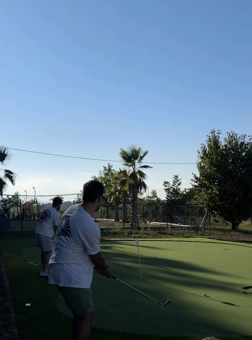 Guests chipping onto the new putting green at Maniero, with palm trees behind