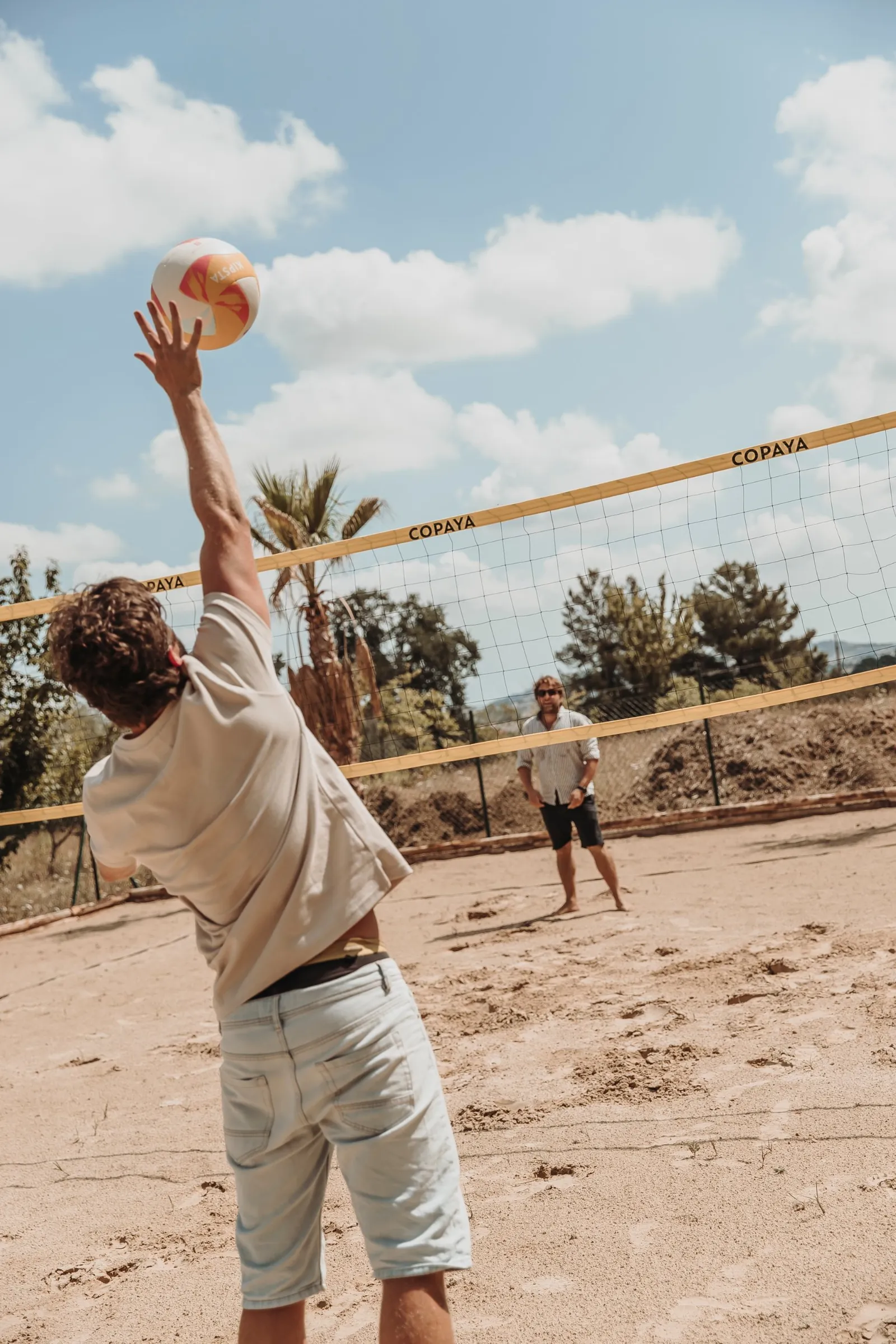 Guests playing beach volleyball on the sand court